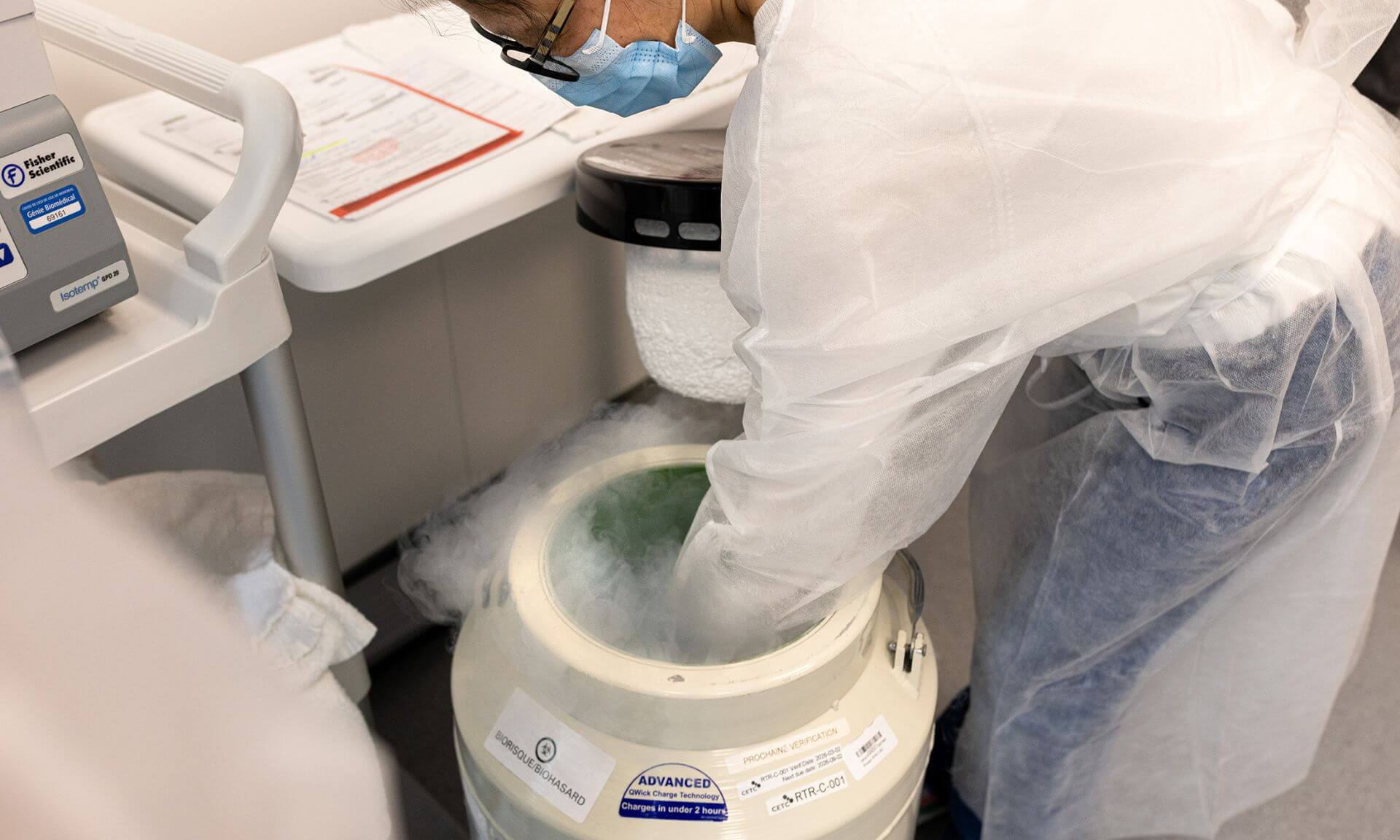 A laboratory technologist in the cell therapy lab handles a transport container for cell products filled with liquid nitrogen.