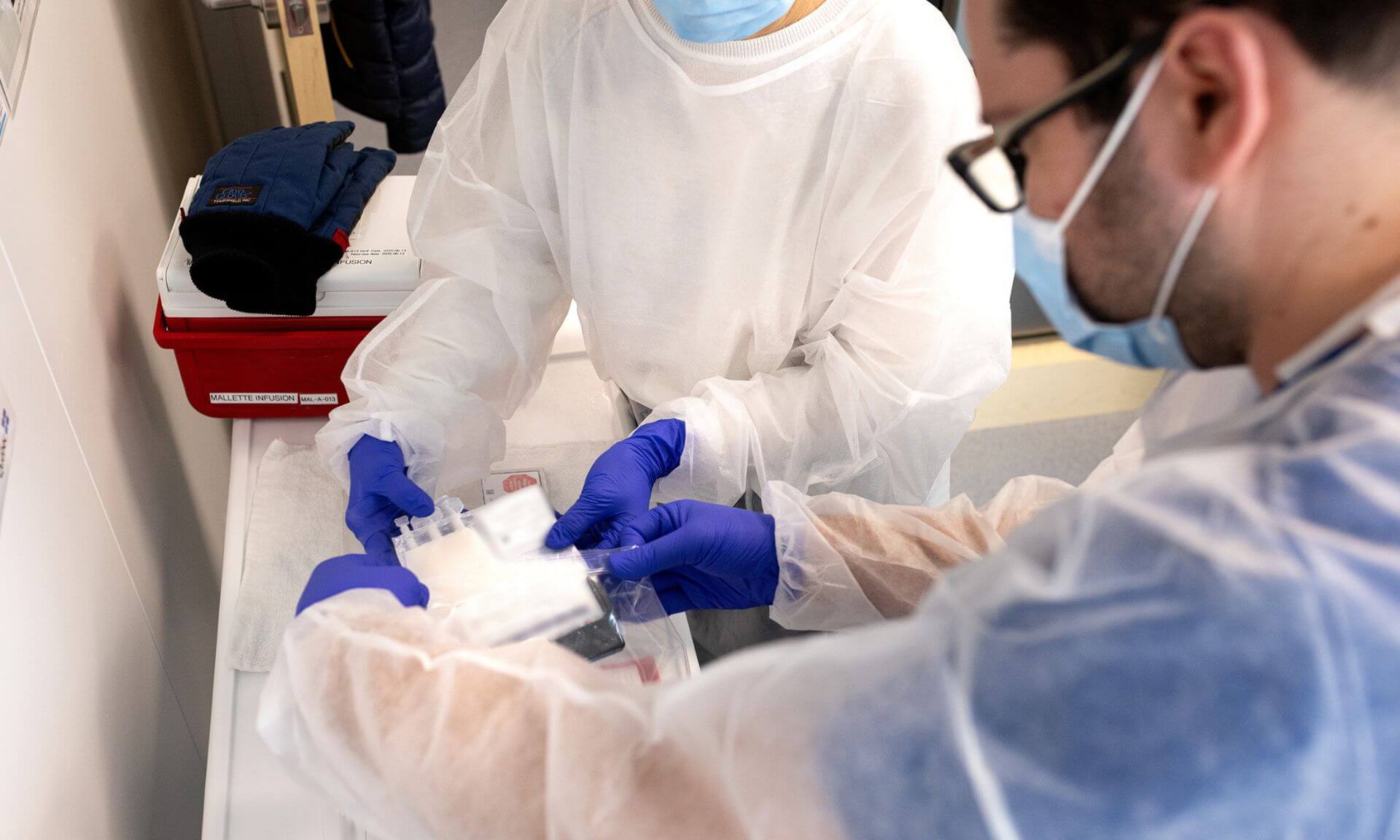 A cell graft is handed over by staff from the cell therapy laboratory to nurse Francis Delisle, who will administer it to the patient.