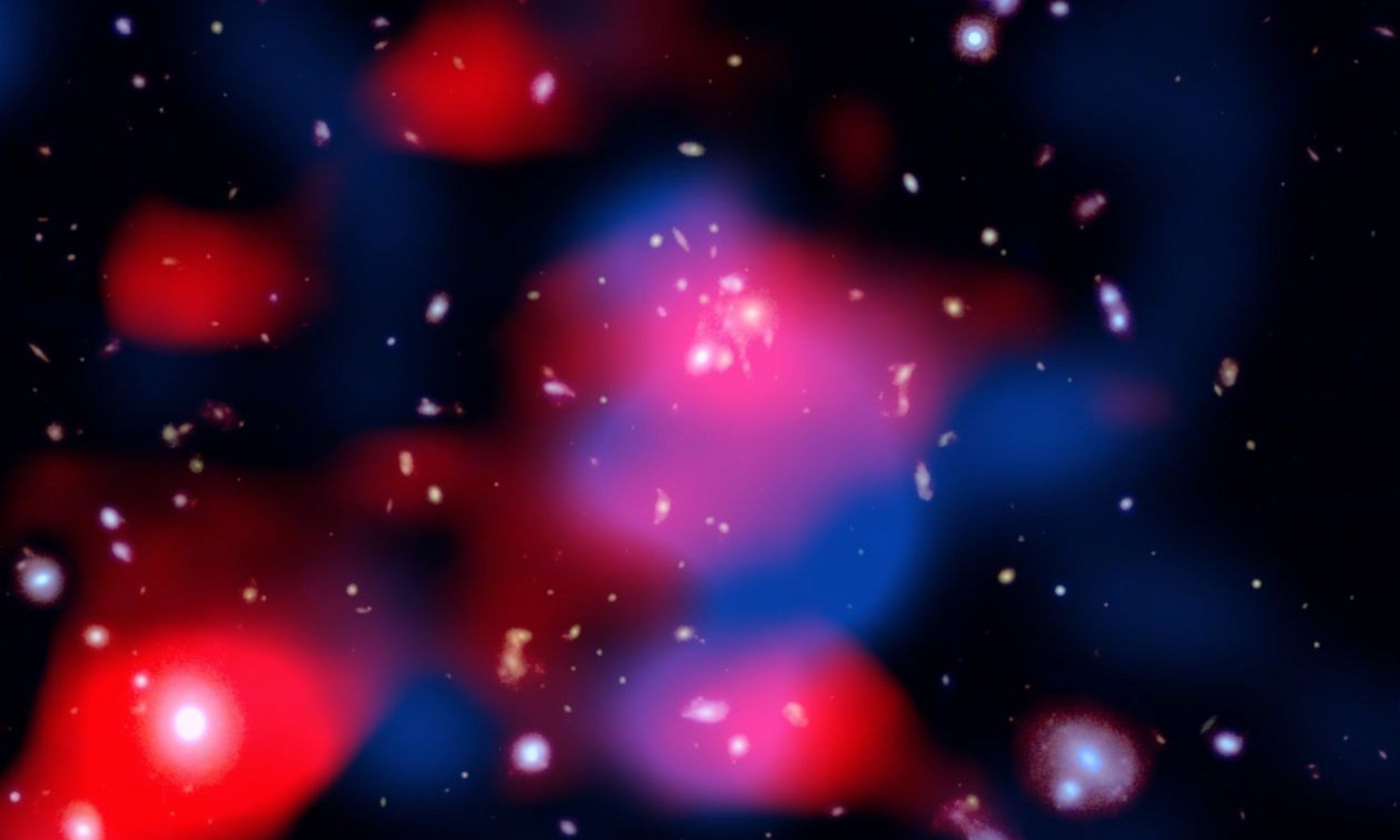 Cette image saisissante dévoile un amas de galaxies lointain débordant d’énergie : les galaxies brillent en lumière visible (blanc), des nuages rougeâtres révèlent un mini-halo radio nouvellement découvert — le plus lointain jamais détecté — et des filaments bleus tracent le gaz chaud émettant en rayons X.