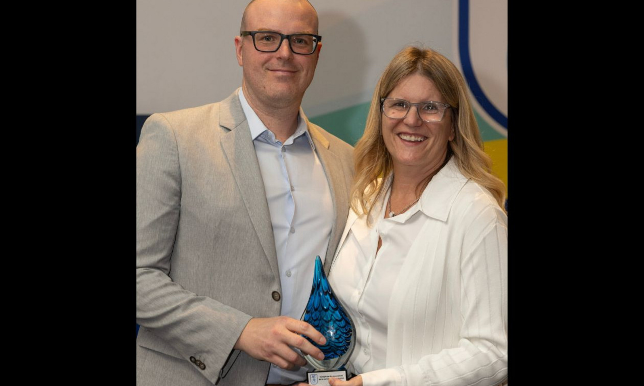 Francis Ménard, directeur général de la Fédération de natation du Québec, remet à Manon Simard, directrice générale du CEPSUM, le prix hommage posthume à Gilles Durocher pour son rôle de bâtisseur pour la natation au Québec.